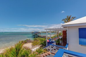 A coastal property with a covered outdoor seating area, a boat dock, and a view of the sea.