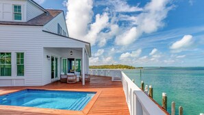 A white house with a wooden deck, a swimming pool, and a view of the ocean. - The Abaco Inn (Hope Town)