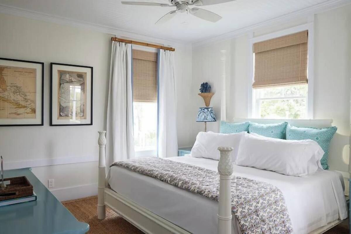 A neatly arranged bedroom with a bed, a nightstand, a lamp, and framed pictures on the wall.
