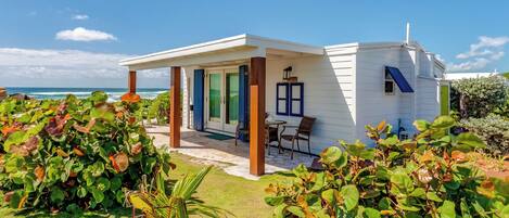 A coastal house with a covered patio, a small deck, and a view of the ocean.