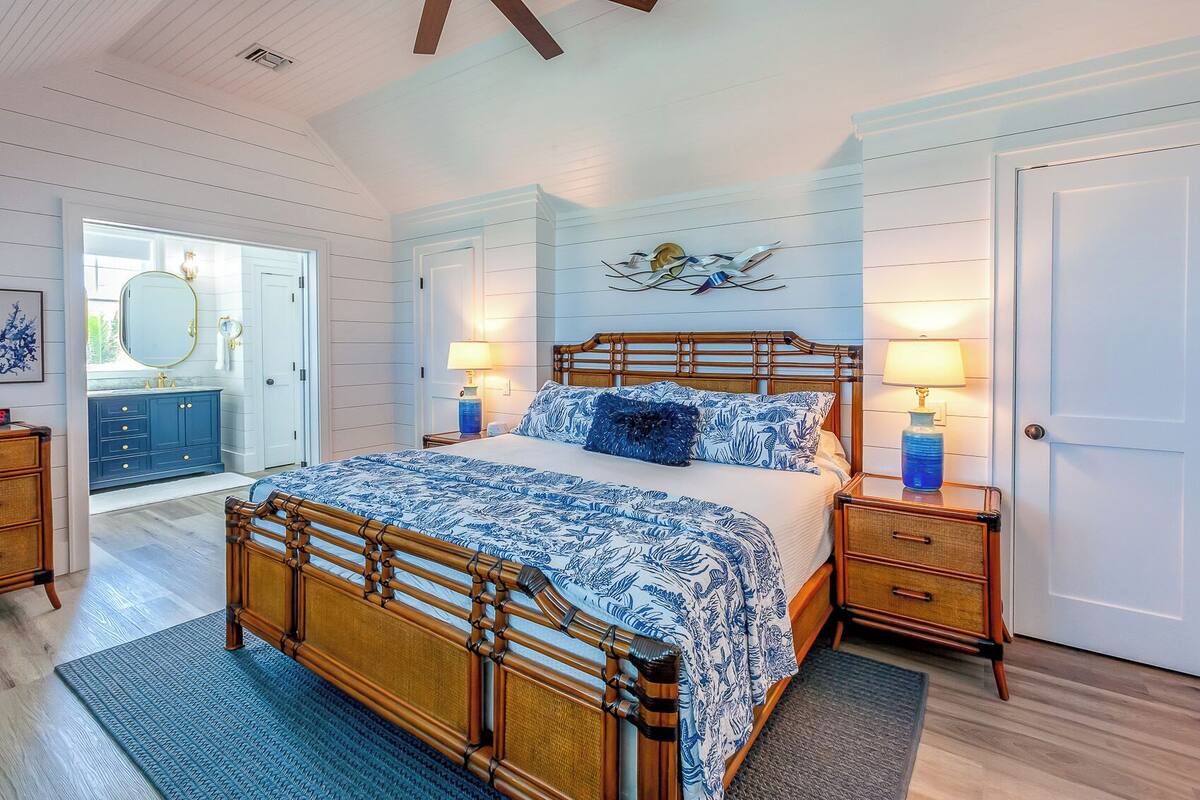 A bedroom with a wooden bed, two bedside tables, a wall-mounted artwork, and a door.