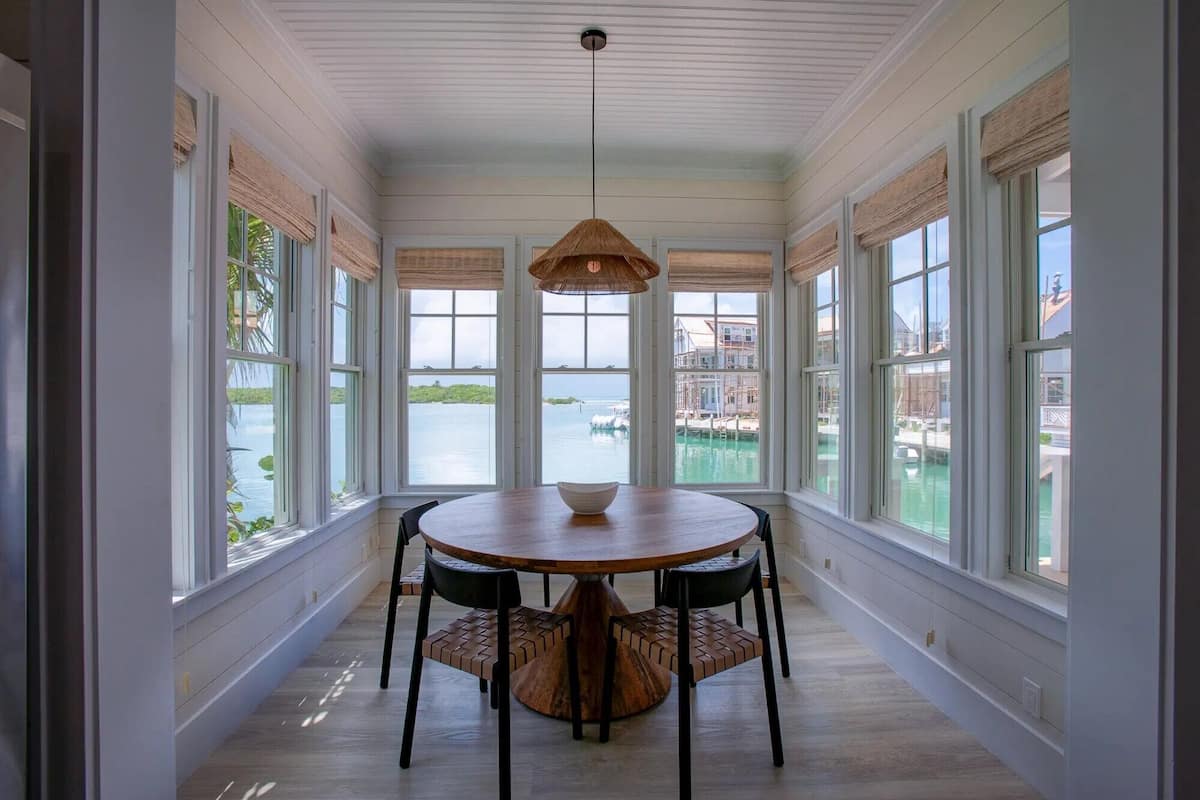 A dining area with a round table, four chairs, and a hanging light fixture.
