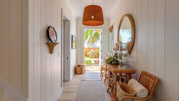A hallway with a dining area featuring wicker furniture and a large mirror.