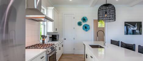 A modern kitchen with white cabinetry, stainless steel appliances, and a central island.