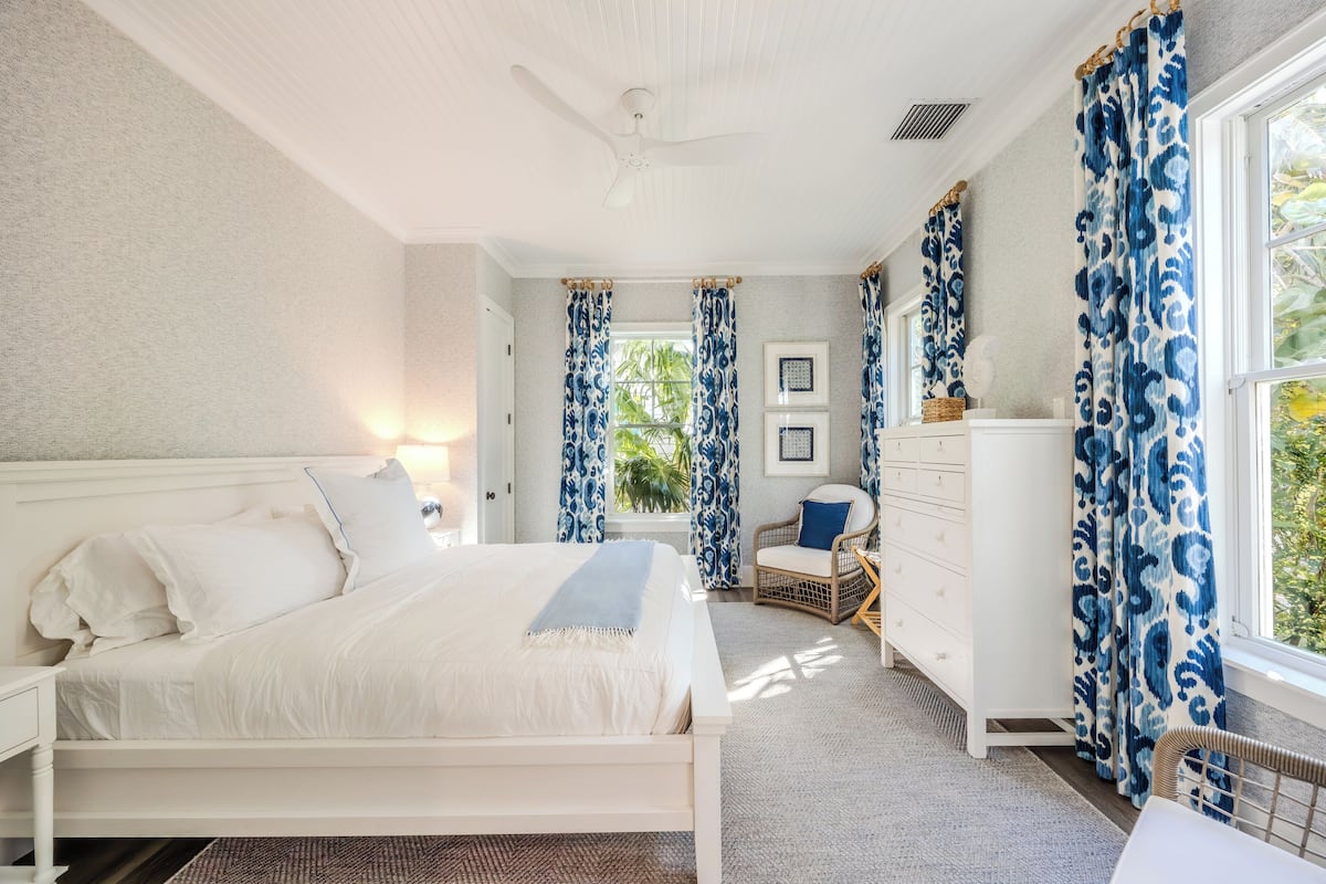 A bedroom with a bed, a dresser, a chair, and a window with curtains.