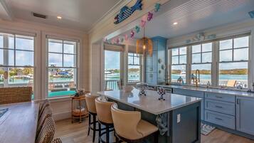 A spacious kitchen with large windows overlooking a marina, featuring a central island with bar stools and decorative items.