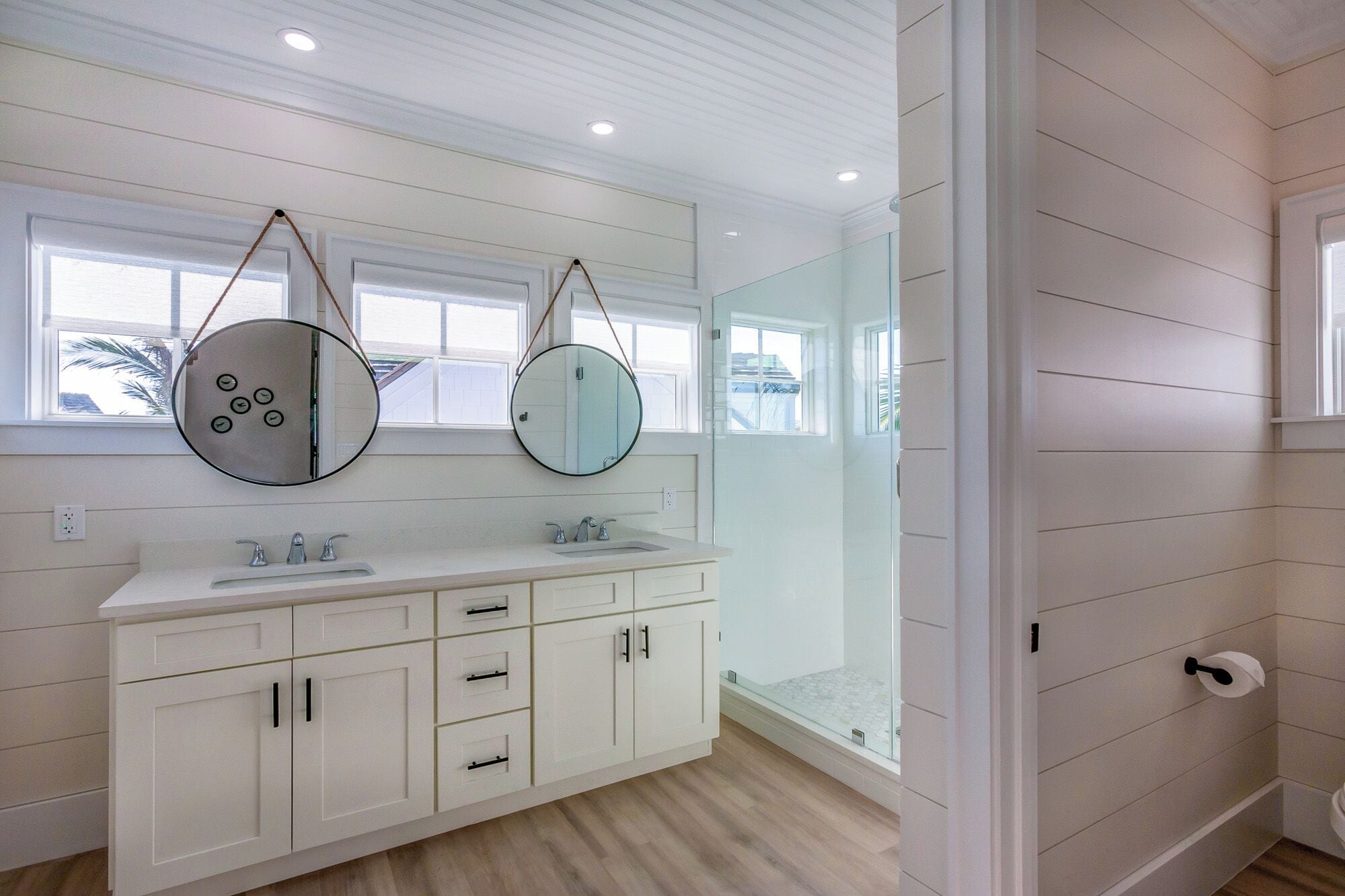 Une salle de bain moderne avec deux lavabos, une douche à l’italienne et un grand miroir.