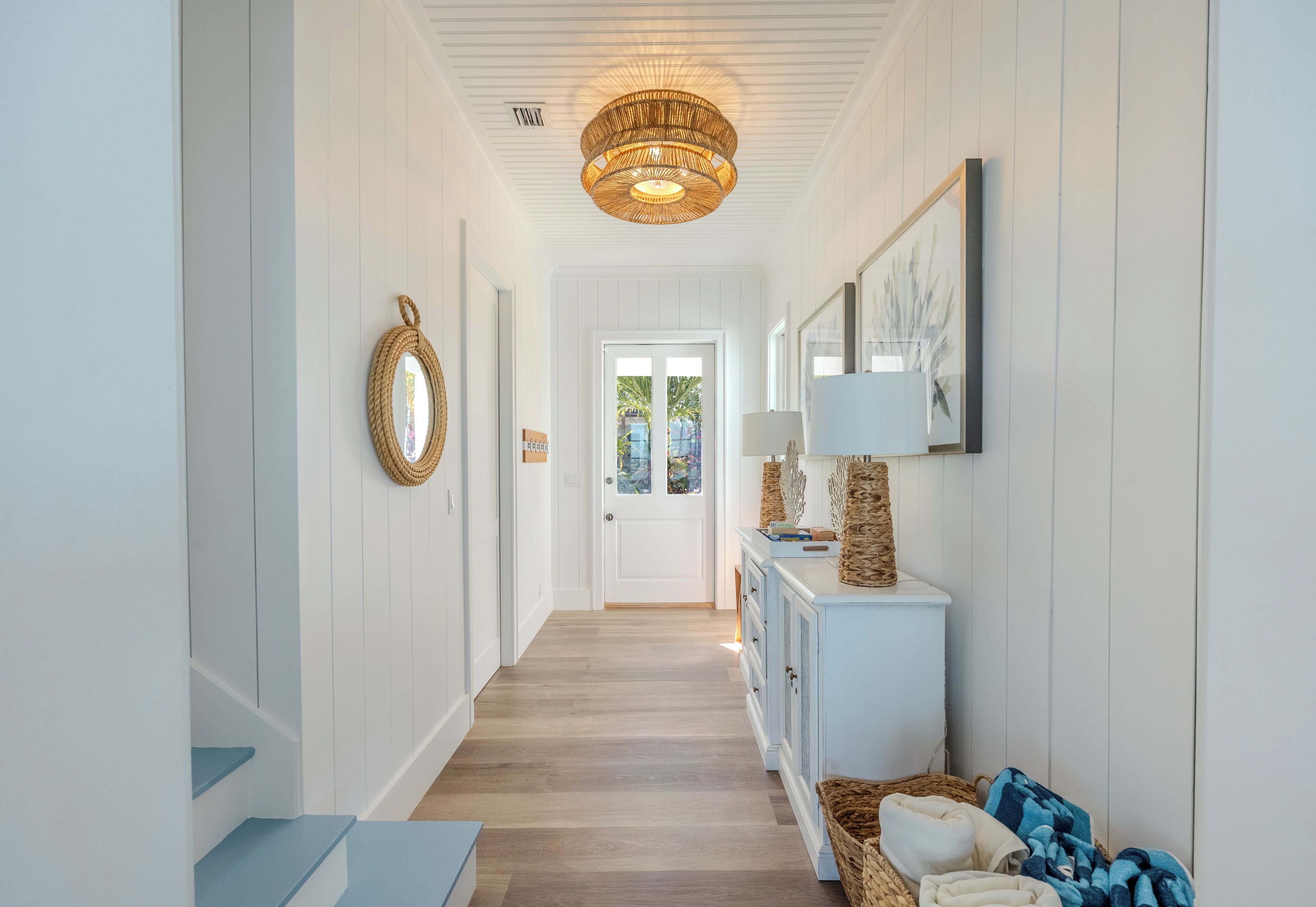 A hallway with a white door at the end, a wicker lamp, and a wicker basket.