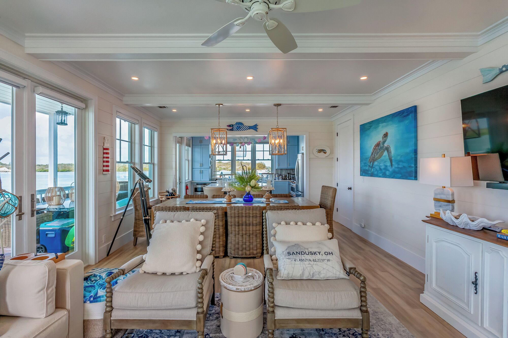 A spacious living room with a large dining table, comfortable seating, and a view of the kitchen.