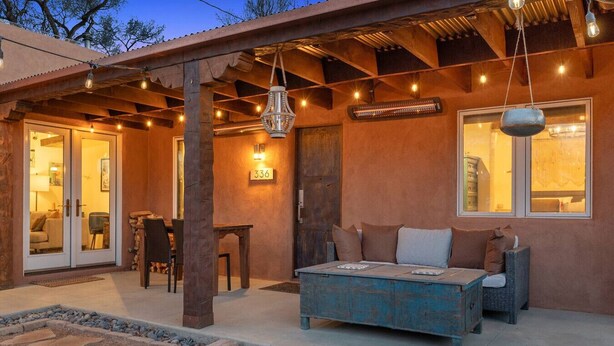 Ein gemütlicher Außenbereich mit einer rustikalen Holz-Pergola, einem blauen Sofa und einem Esstisch.
