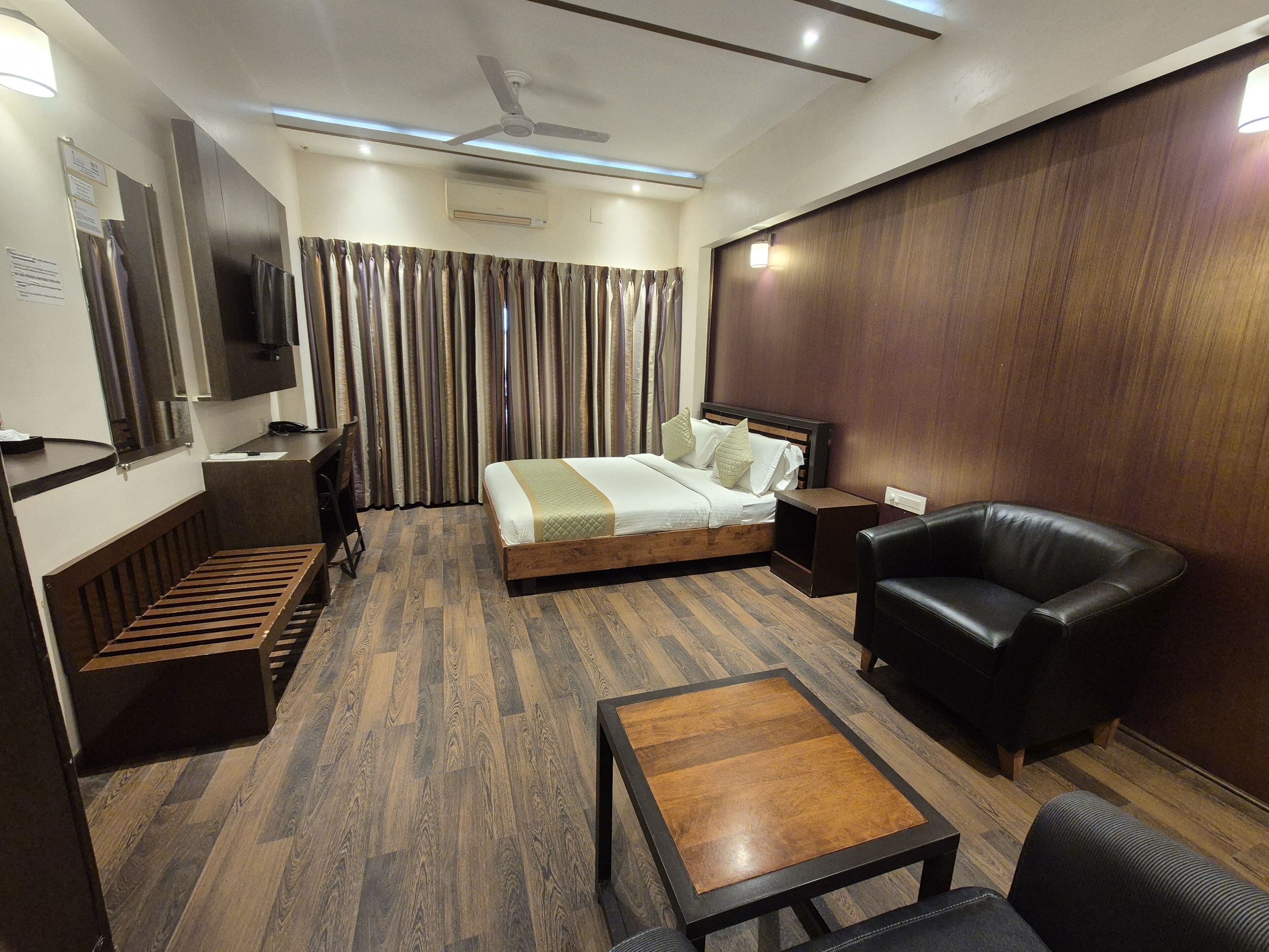 Een hotelkamer met een bed, een bureau, een stoel, een salontafel en een televisie.