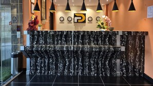 A reception desk with a marble top, black pendant lights, and clocks displaying times from Dubai, Sydney, London, and Bangkok. - R D HOTELS HSR (Bengaluru)