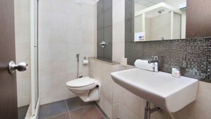 A bathroom with a toilet, sink, and shower. - R D HOTELS HSR (Bengaluru)