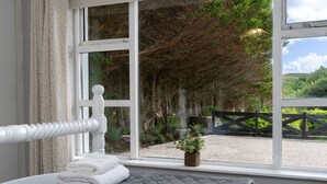 Ein Schlafzimmer mit einem großen Fenster, einem Bett mit gesteppter Bettdecke und einem kleinen Topfpflanzen auf der Fensterbank.