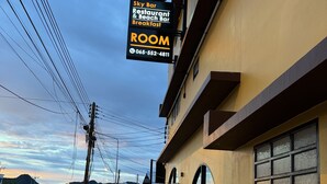 A building with a sign for 'Sky Bar Restaurant & Beach Bar Breakfast' and a 'ROOM' sign with a phone number. - Phoenix Room (Pathio)