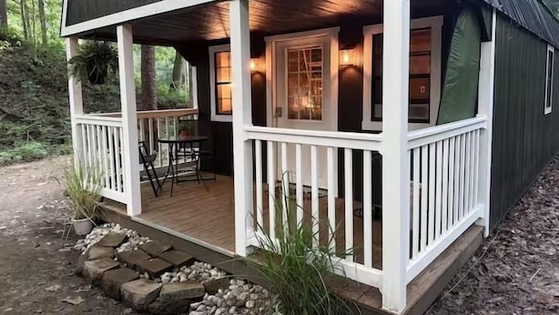 A cabin with a porch, a table, and chairs.