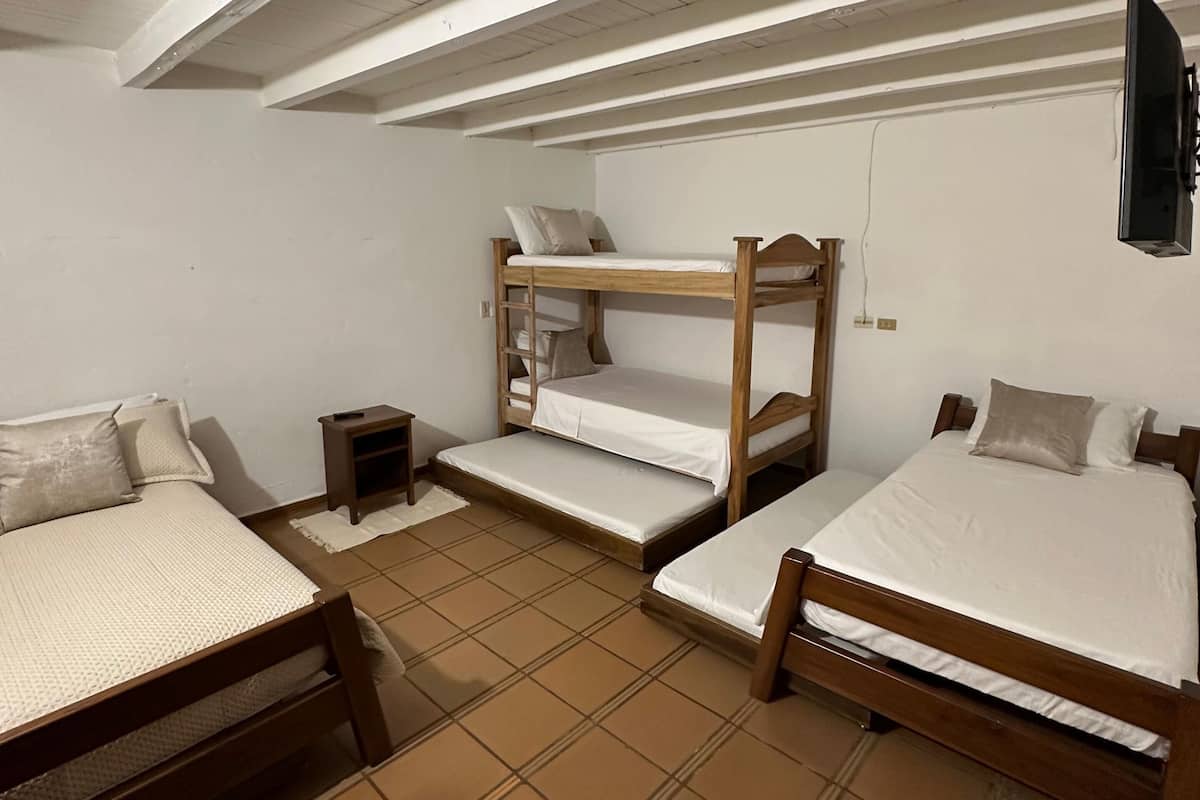 Una camera in stile dormitorio con letti a castello, un comodino e una TV fissata al muro.