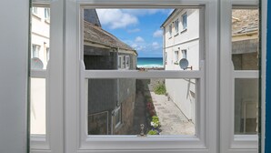 A view through a window of a narrow street with buildings on either side and a clear blue sky.
