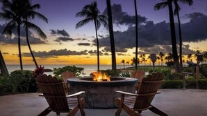 A fire pit with two wooden chairs, overlooking a beach with palm trees and a sunset. - View Stunning Sunsets in this Ocean View 1 Br @ MVC Ko Olina Beach Club (Kapolei)