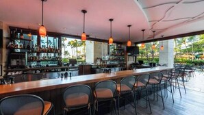 A bar area with multiple seating options, a bar counter, and a view of the outdoors. - View Stunning Sunsets in this Ocean View 1 Br @ MVC Ko Olina Beach Club (Kapolei)