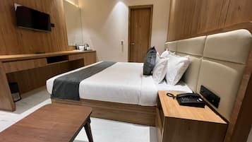 A modern hotel room with a bed, bedside table, and a desk area.