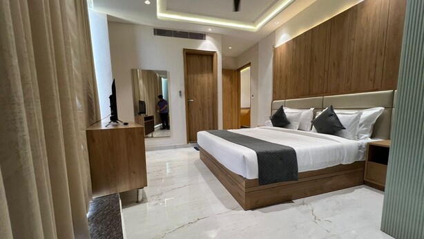 Una habitación de hotel moderna con una cama grande, cabecero de madera y un televisor sobre un mueble de madera.