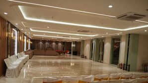 Un salón amplio con filas de sillas y un escenario, que presenta un piso pulido e iluminación moderna.