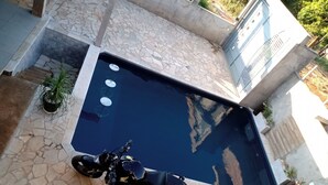 Ein Pool mit Steinplatten umgeben, in der Nähe ein abgestelltes Motorrad.