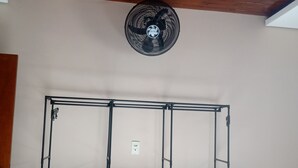 Ein Zimmer mit einem Metallregal, einem Deckenventilator und einem kleinen Hocker.