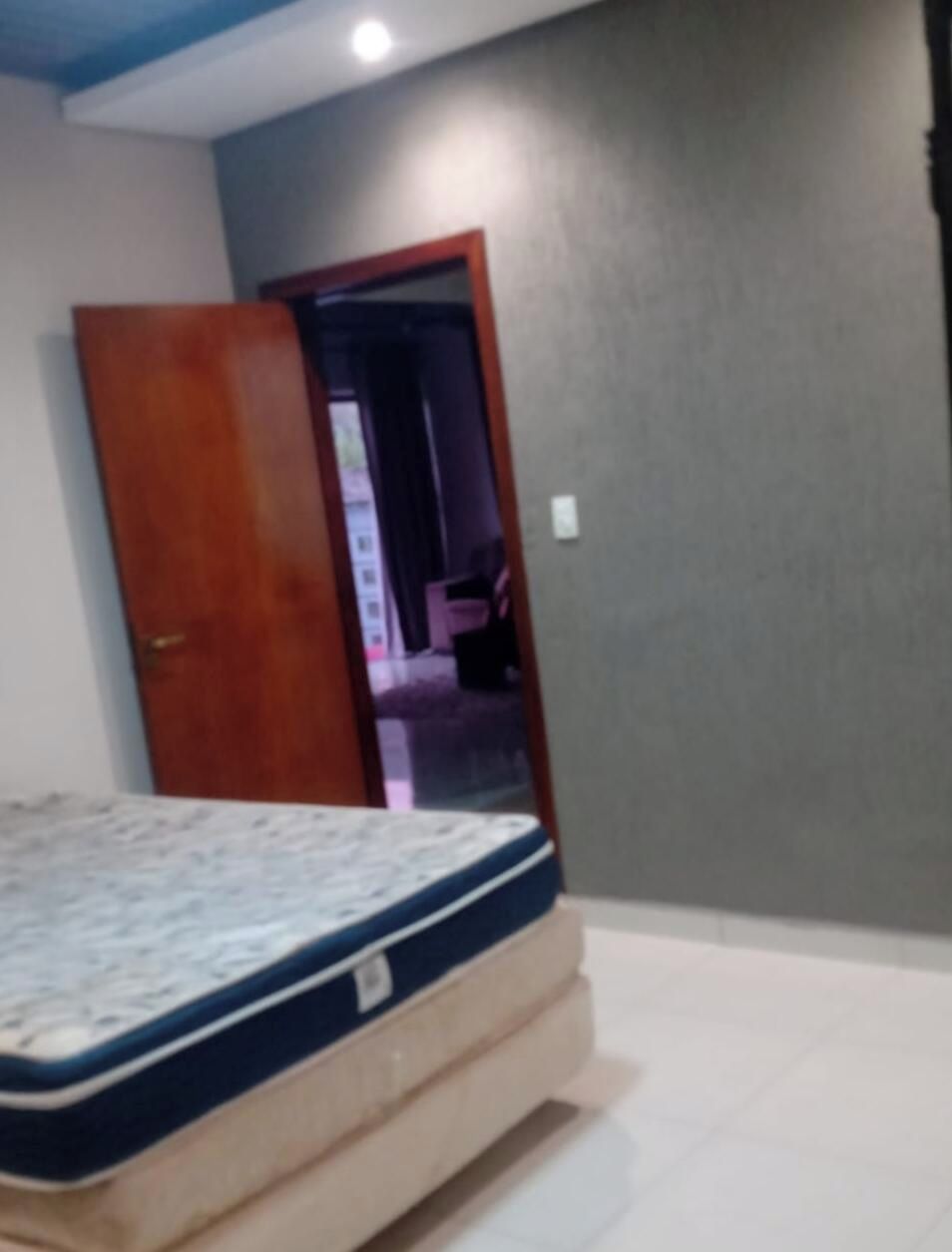 A bedroom with a bed, a wooden door, and a grey wall.