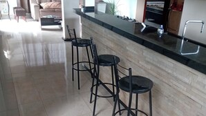 Eine moderne Küche mit schwarzem Arbeitsplatz, drei schwarzen Barhocker und einer Holzrückwand.