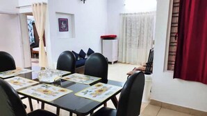 A dining area with a table set for four, black chairs, and a white cabinet in the background.