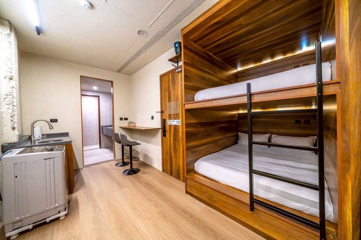 Una habitación compacta con literas, un pequeño kitchenette y una zona de estar con dos sillones.