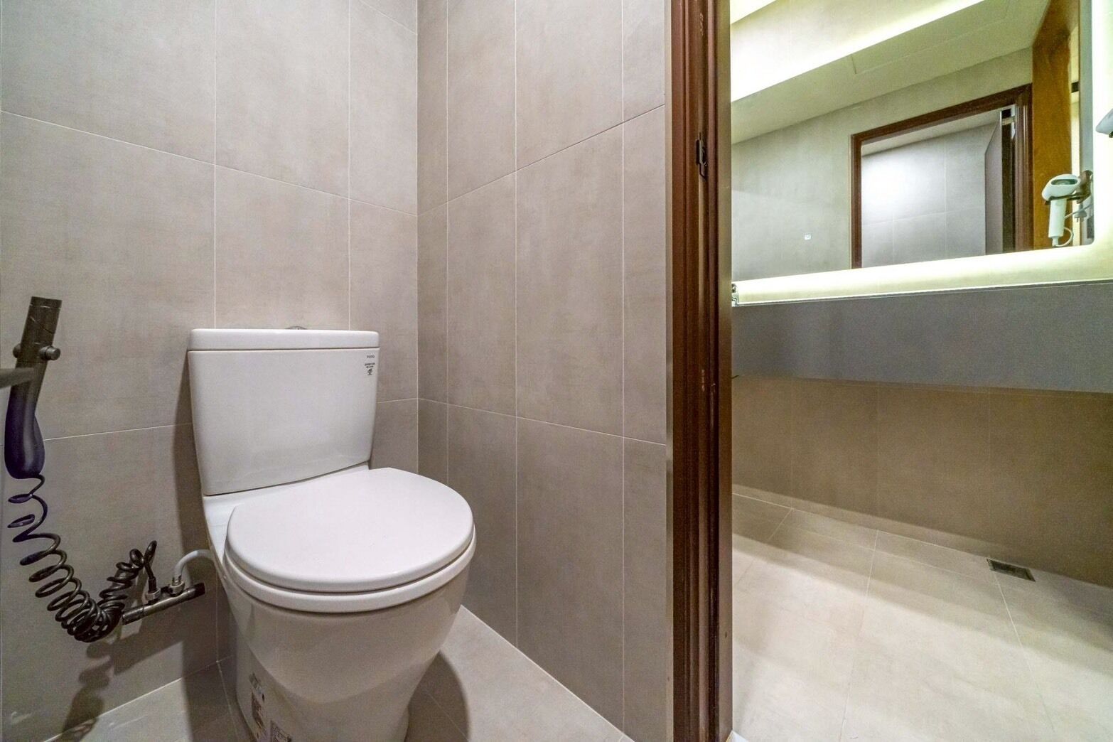 A bathroom with a toilet, a shower area, and a mirror.