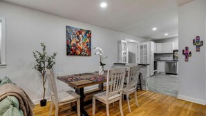 A dining area with a wooden table and chairs, a colorful painting on the wall, and a potted plant. - Vibrant Fiesta-Style Retreat (San Antonio)