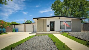 A single-story house with a garage, a front porch, and a small garden area. - Vibrant Fiesta-Style Retreat (San Antonio)