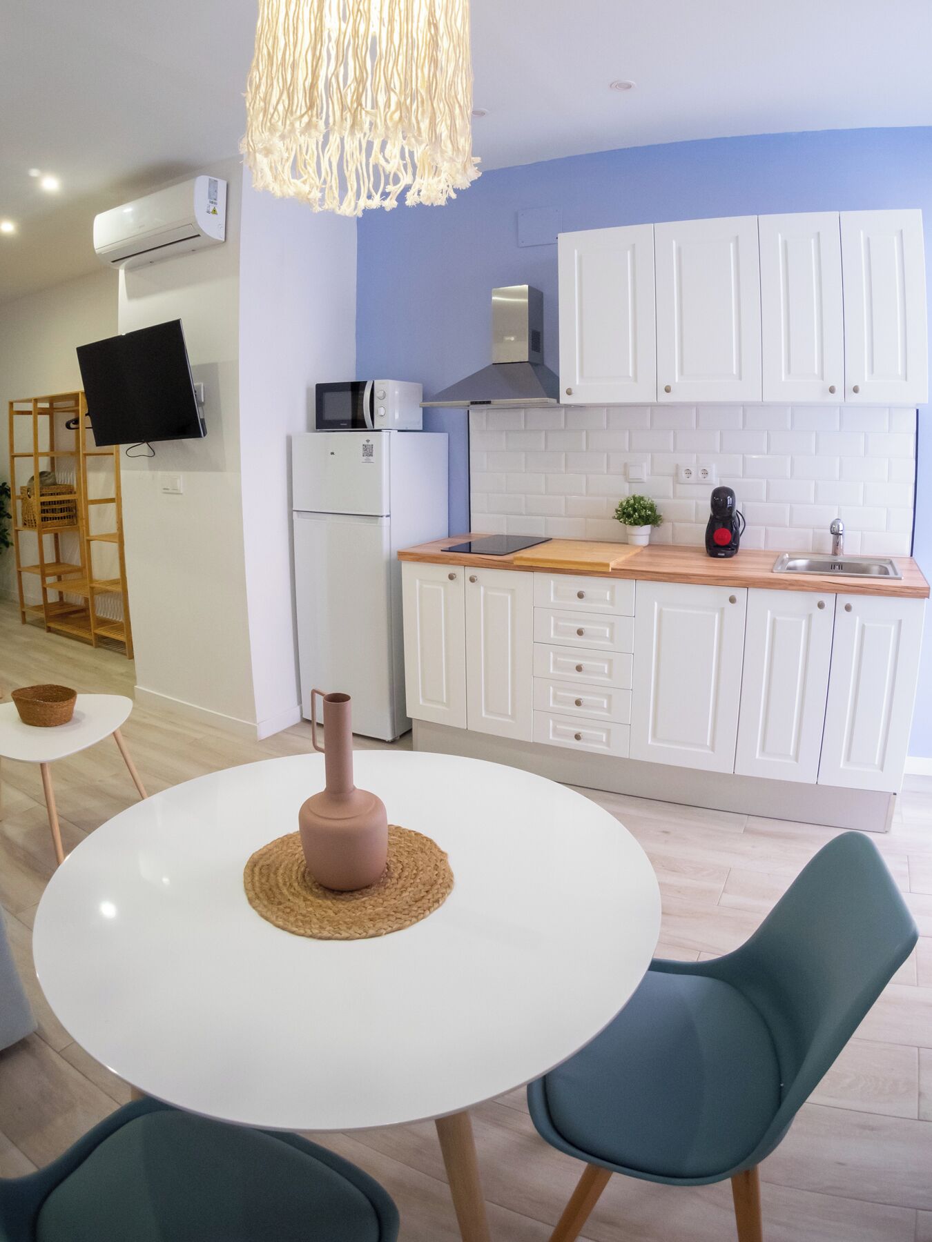 A modern kitchen with white cabinets, a microwave, a coffee maker, and a hanging light fixture.