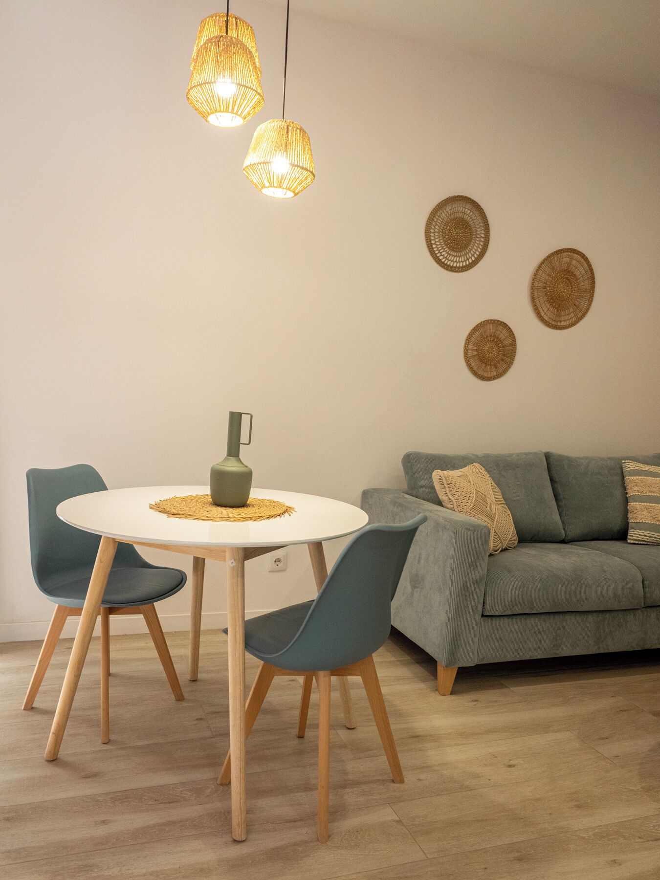 A dining area with a round table, two chairs, and hanging pendant lights.