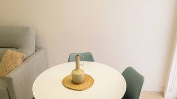 A dining area with a round white table, two chairs, a woven placemat, and a candle holder.
