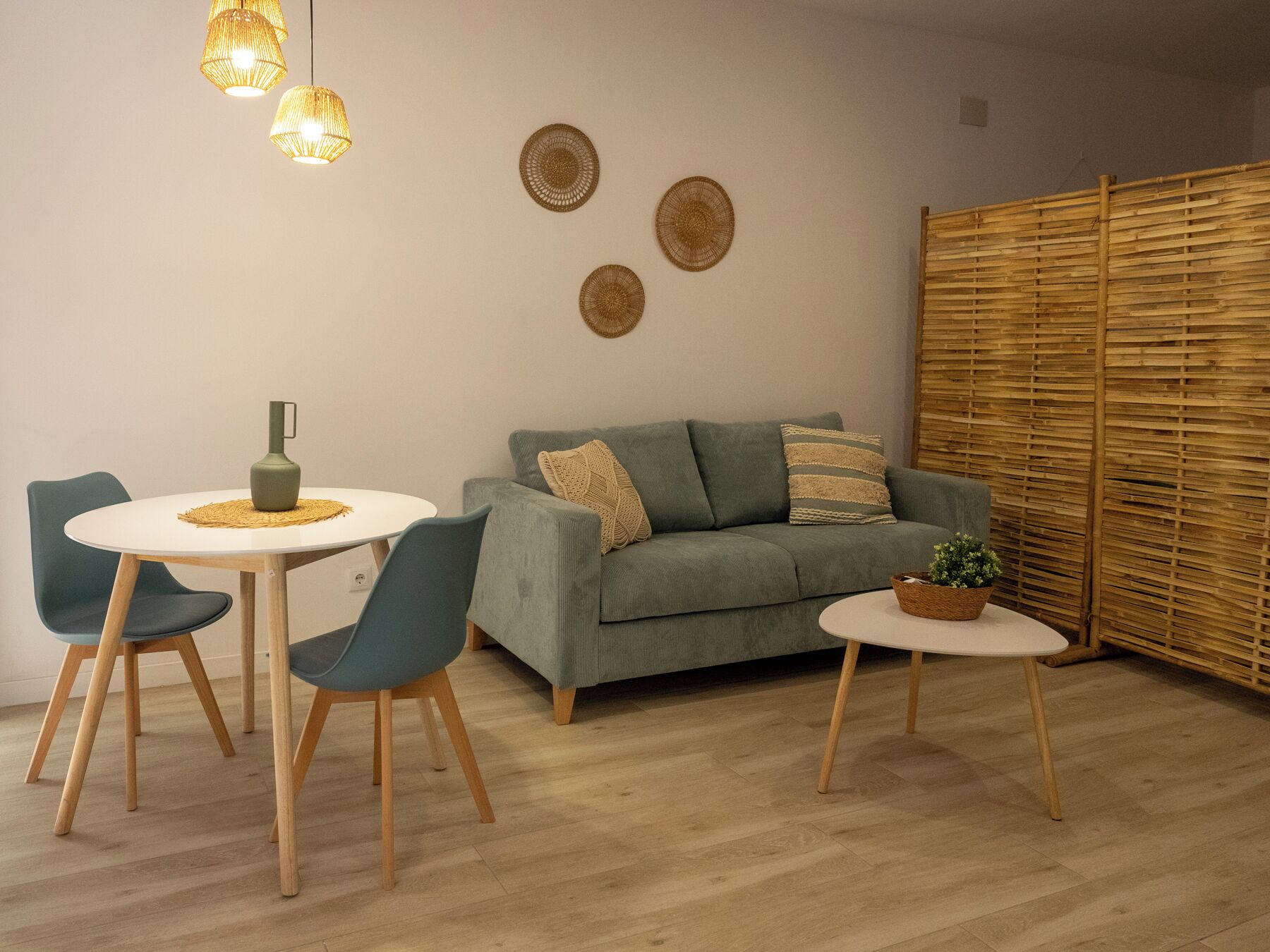 A cozy living area with a sofa, two chairs, a small table, and a decorative wall with woven items.