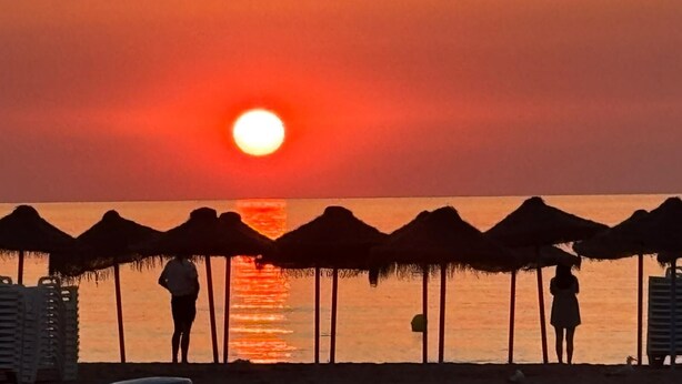 A beach scene with a sunset, beach umbrellas, and people. - Boho Beach Flats (València)