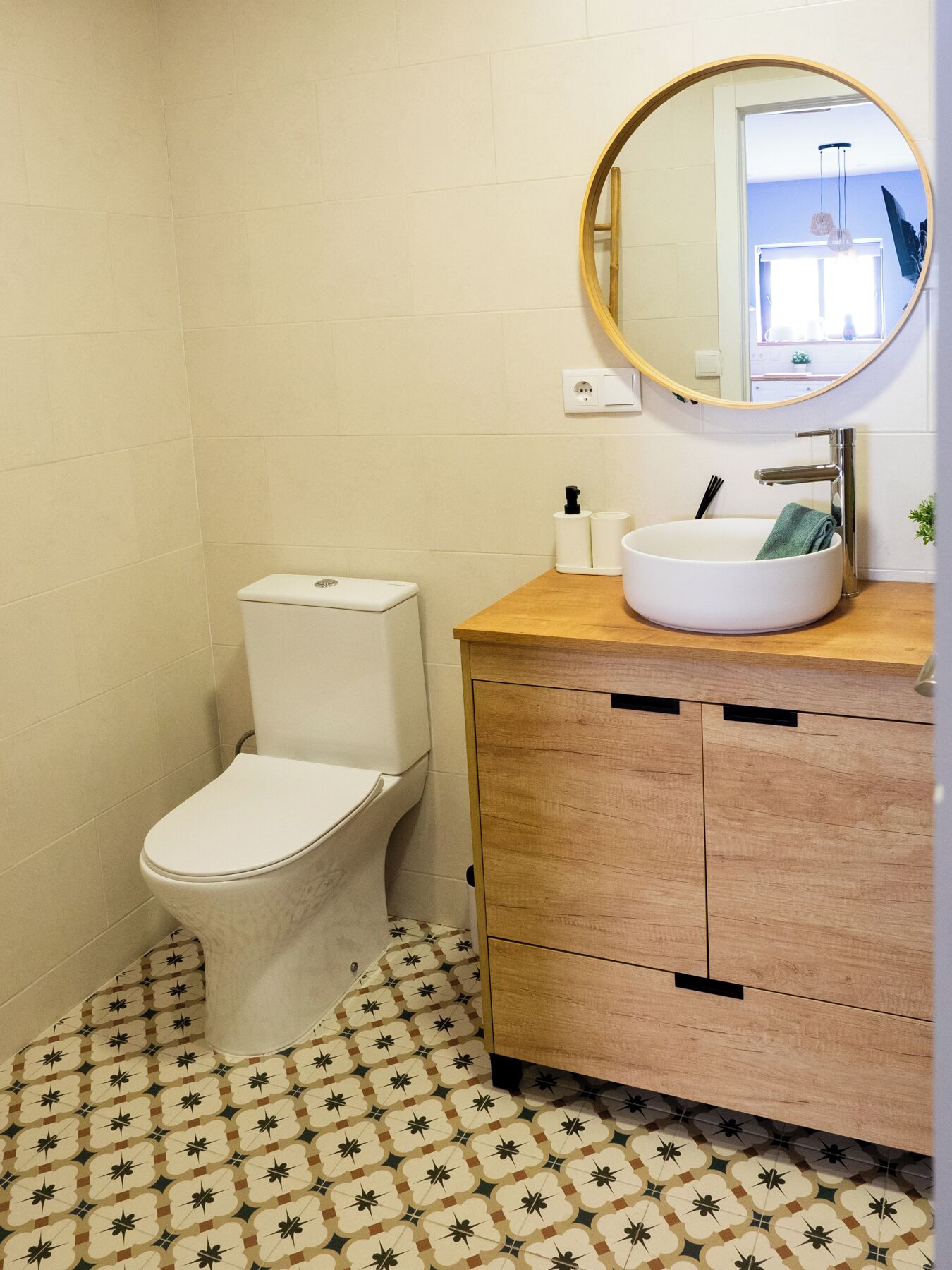 Un bagno con il water, un lavandino con uno specchio e piastrelle decorative sul pavimento.