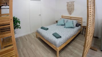 Ein Schlafzimmer mit einem hölzernen Bett, einem Deckenventilator, einem Wandbehang aus Makramee und einer Holzvertäfelung.