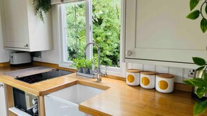 A modern kitchen with a built-in oven, a sink, and a window with a view of greenery. - STUNNING SHEPHERDS HUT WITH HOT TUB IN BEAUTIFUL RURAL CHESHIRE, NEAR NANTWICH (Nantwich)