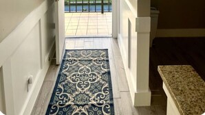 A hallway with a patterned rug leading to a balcony with a view of a residential area. - Beach Front Condo with Breathtaking Views (Jensen Beach)