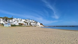 A sandy beach with white buildings in the background. - Family apartment with private garden, swimming pool and close to the beach - Cabo Negro (Cabo Negro)