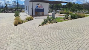 A paved area with a building labeled "KIDS CLUB" and a covered seating area. - Family apartment with private garden, swimming pool and close to the beach - Cabo Negro (Cabo Negro)