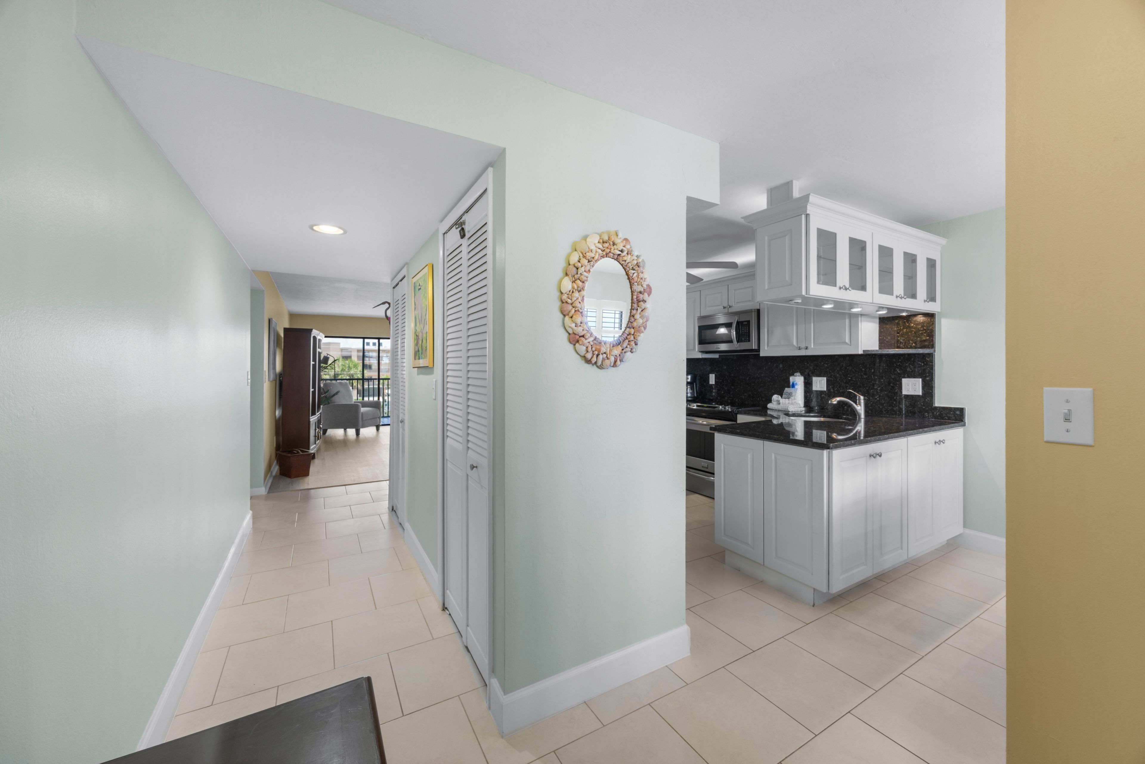 A modern kitchen with white cabinets, a black countertop, and a stainless steel sink.