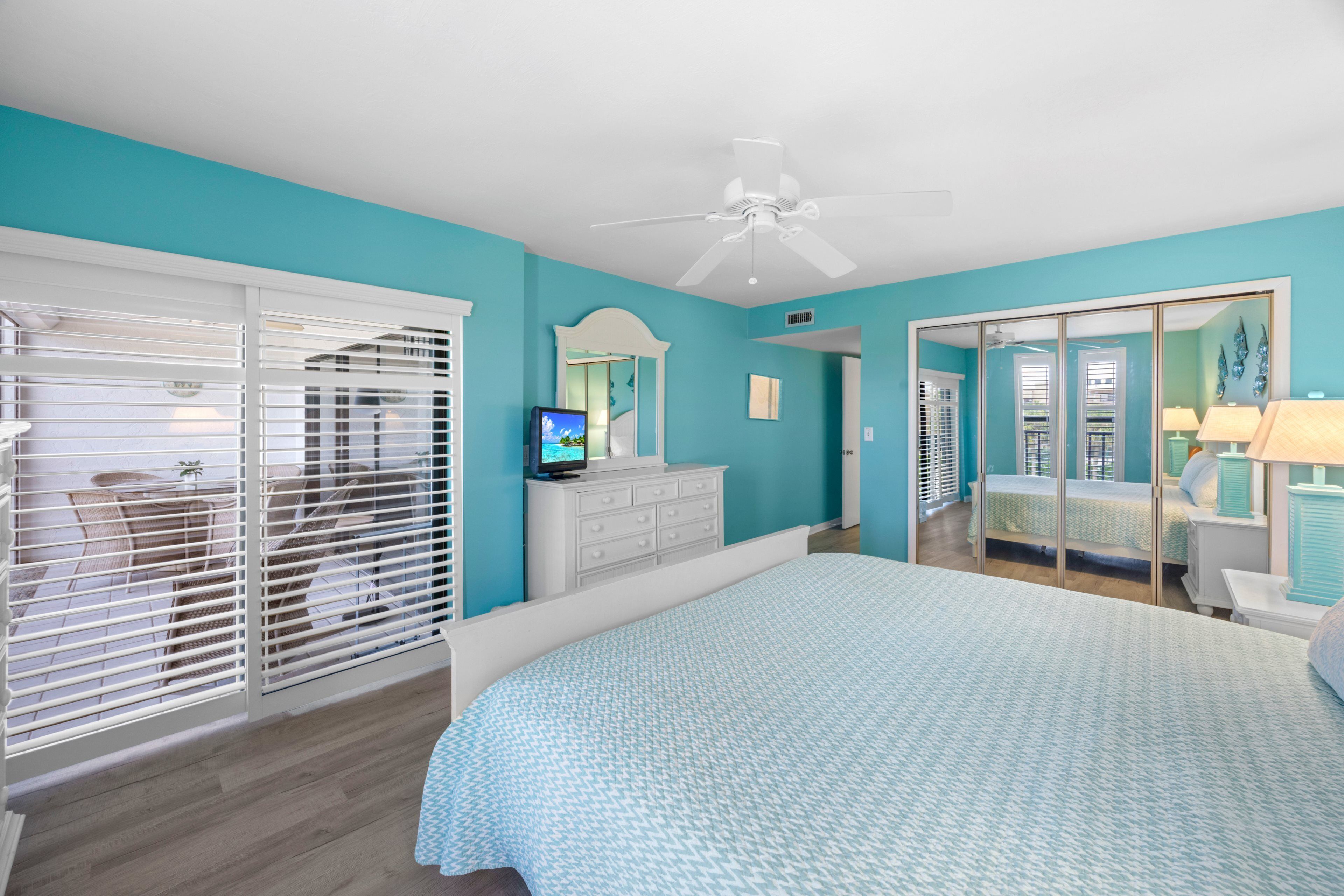 A bedroom with a bed, a dresser, a television, and a ceiling fan.