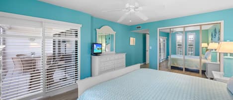 A bedroom with a bed, a dresser, a television, and a ceiling fan.